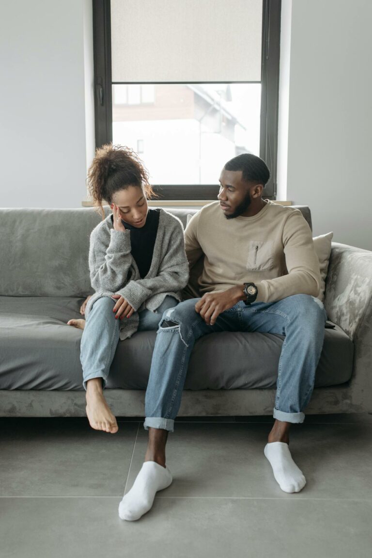 Concerned couple sitting indoors, addressing health issues and comfort together.