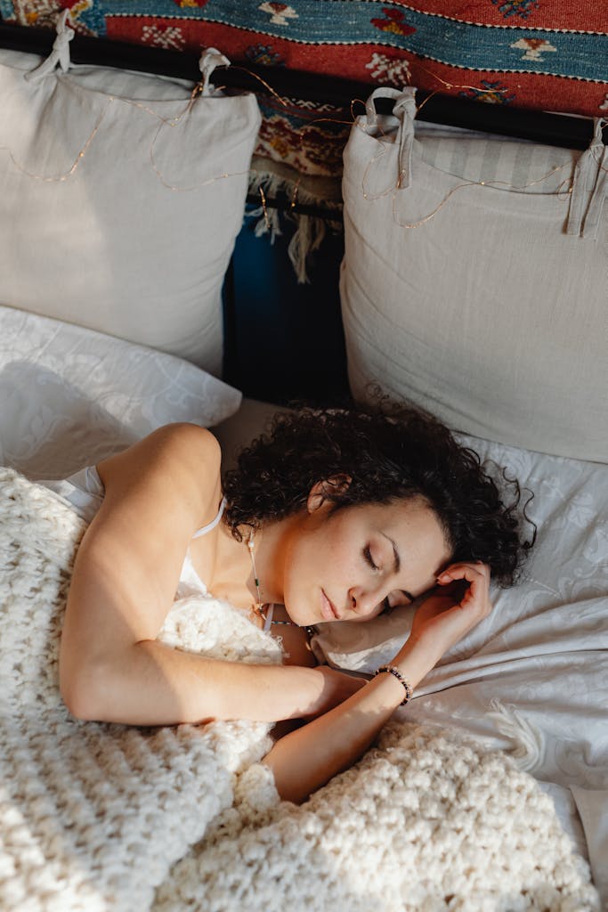 Serene scene of a woman sleeping peacefully in bed with a knitted blanket.
